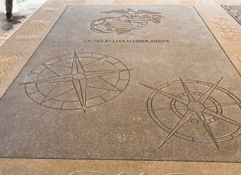 A skilled worker applying a designer stencil pattern to a concrete floor